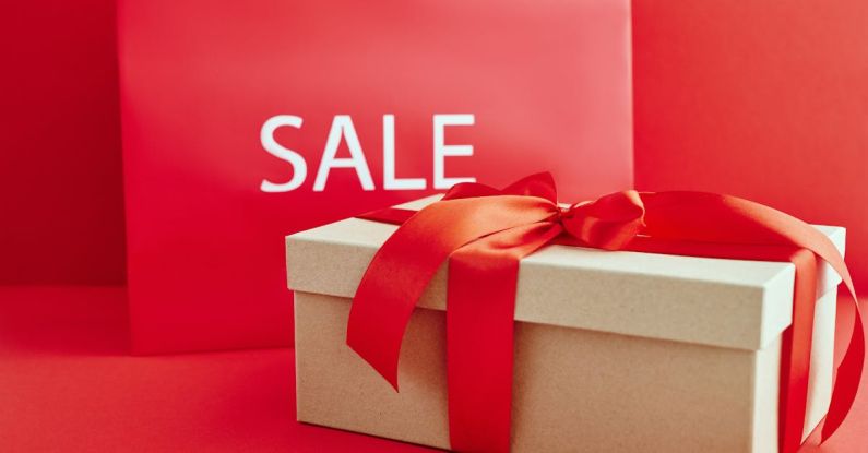 Luxury Shopping - Cardboard Box with Red Ribbon Beside A Sale Sign