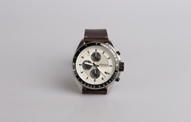 Watch - round silver-colored Fossil chronograph watch at 9:22 with brown leather band